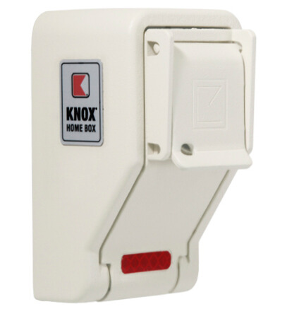 A white metal Knox Home Box with a protective cover, a Knox logo on the left, and a small red reflector at the bottom. The box is used for secure key storage.